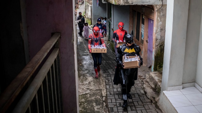 Anggota Komunitas Badut Cimahi mengenakan kostum superhero membawa paket takjil untuk dibagikan kepada warga di Kota Cimahi, Jawa Barat, Senin (23/2/2026). [ANTARA FOTO/Abdan Syakura/rwa]