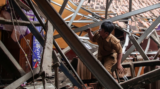 Guru memeriksa kondisi ruang kelas yang atapnya ambruk di SD Negeri Jomin Barat III, Kecamatan Kota Baru, Karawang, Jawa Barat, Selasa (24/2/2026). [ANTARA FOTO/Darryl Ramadhan/nym]