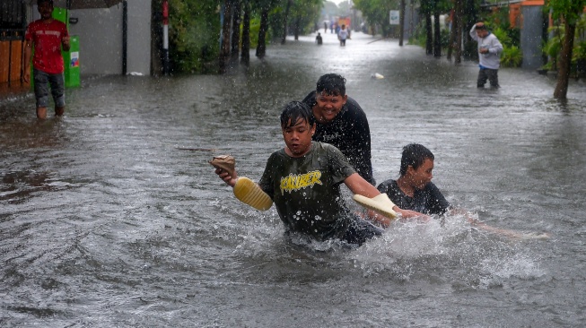 Sejumlah anak bermain di tengah banjir di Denpasar, Bali, Selasa (24/2/2026). [ANTARA FOTO/Nyoman Hendra Wibowo/nym]