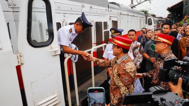 Menteri Perdagangan Budi Santoso (tengah) bersama Menteri Perhubungan Dudy Purwagandhi  (kanan) ?memberikan produk UMKM Lokal di kepada masinis kereta KA Argo Sindoro di Stasiun Gambir, Jakarta, Selasa (24/2/2026). [Suara.com/Alfian Winanto]
