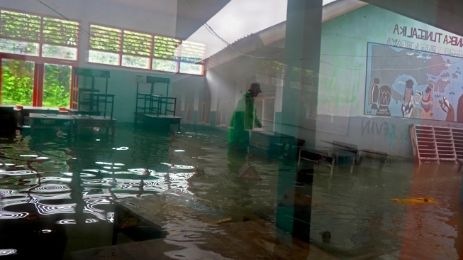 Seorang siswa memindahkan kursi dan meja di dalam kelas yang terendam banjir di SMA Negeri 19 Makassar, Sulawesi Selatan, Rabu (25/2/2026). [ANTARA FOTO/Hasrul Said/tom]
