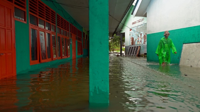 Seorang siswa berjalan melintasi genangan air di pekarangan sekolah saat banjir merendam SMA Negeri 19 Makassar, Sulawei Selatan, Rabu (25/2/2026). [ANTARA FOTO/Hasrul Said/tom]
