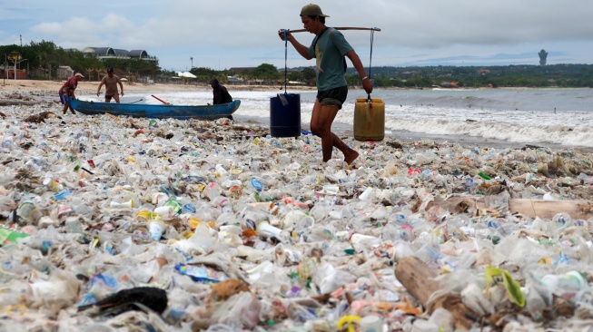 Nelayan mengangkut air melewati tumpukan sampah kiriman di Pantai Kedonganan, Badung, Bali, Kamis (26/2/2026). [ANTARA FOTO/Nyoman Hendra Wibowo/rwa]