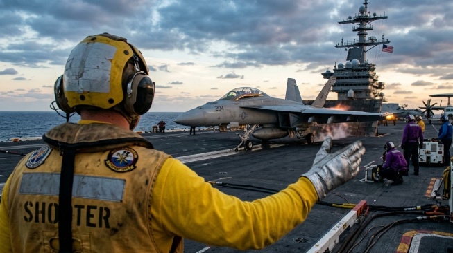 Ilustrasi awak kapal induk yang sedang memandu pesawat lepas landas. (Gemini AI)