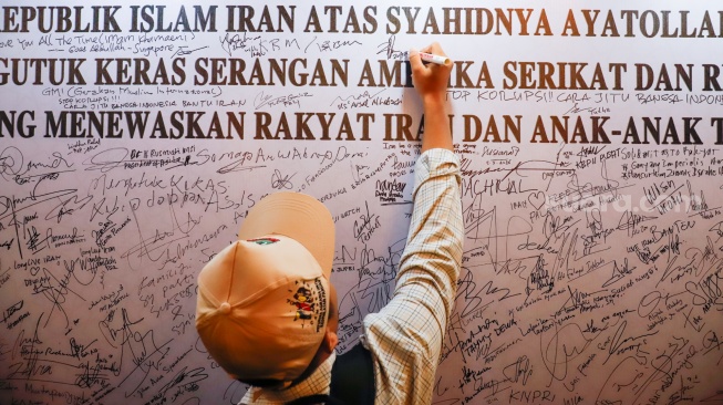 Warga menuliskan pesan dukungan saat Aksi Solidaritas dan Doa Bersama untuk Iran di Kediaman Duta Besar Iran, Jakarta, Kamis (5/3/2026). [Suara.com/Alfian Winanto]