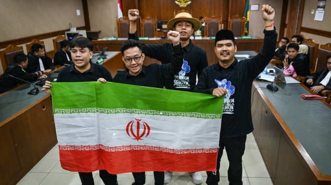 Terdakwa kasus dugaan penghasutan unjuk rasa, Delpedro Marhaen (kedua kiri), Muzaffar Salim (kiri), Syahdan Husein (kanan) dan Khariq Anhar (kedua kanan) membawa bendera Iran sebelum menjalani sidang putusan di Pengadilan Tipikor, Jakarta, Senin (19/1/2026). [ANTARA FOTO/Bayu Pratama S./rwa]