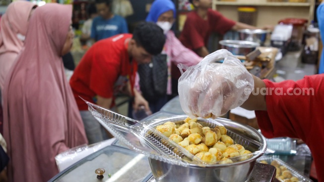 Pedagang melayani pembeli kue kering yang dijual di Pasar Jatinegara, Jakarta, Senin (9/3/2026). [Suara.com/Alfian Winanto]