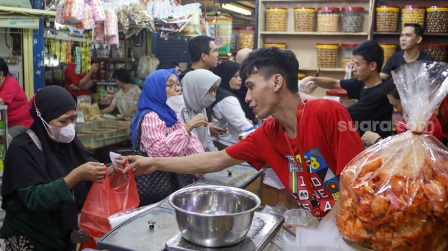 Pedagang melayani pembeli kue kering yang dijual di Pasar Jatinegara, Jakarta, Senin (9/3/2026). [Suara.com/Alfian Winanto]