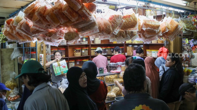 Pedagang melayani pembeli kue kering yang dijual di Pasar Jatinegara, Jakarta, Senin (9/3/2026). [Suara.com/Alfian Winanto]