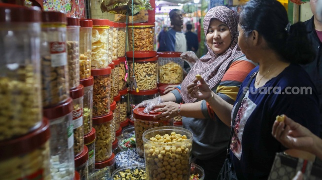 Pedagang melayani pembeli kue kering yang dijual di Pasar Jatinegara, Jakarta, Senin (9/3/2026). [Suara.com/Alfian Winanto]