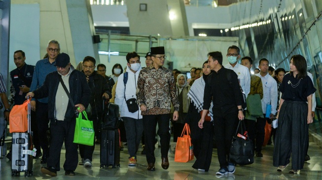 Menteri Luar Negeri Sugiono (tengah) berjalan bersama Warga Negara Indonesia (WNI) yang dievakuasi dari Iran setibanya di Terminal 3 Bandara Soekarno-Hatta, Tangerang, Banten, Selasa (10/3/2026). [ANTARA FOTO/Putra M. Akbar/nym]