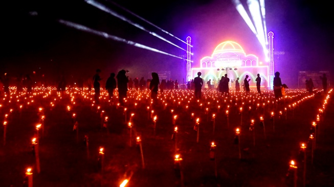 Pengunjung melihat ribuan lampu minyak pada tradisi Tumbilotohe atau malam pasang lampu di Ayula, Kabupaten Bone Bolango, Gorontalo, Senin (16/3/2026). [ANTARA FOTO/Adiwinata Solihin/sgd]