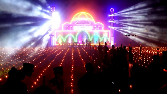 Pengunjung melihat ribuan lampu minyak pada tradisi Tumbilotohe atau malam pasang lampu di Ayula, Kabupaten Bone Bolango, Gorontalo, Senin (16/3/2026). [ANTARA FOTO/Adiwinata Solihin/sgd]