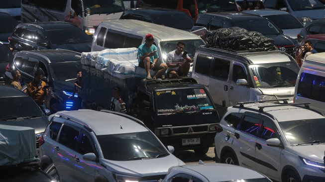 Pemudik duduk di atas kendaraannya saat antre memasuki kapal di Pelabuhan Merak, Kota Cilegon, Banten, Rabu (18/3/2026). [ANTARA FOTO/Angga Budhiyanto/foc]