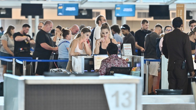 Penumpang pesawat antre di tempat lapor diri Terminal Keberangkatan Internasional Bandara Internasional I Gusti Ngurah Rai, Badung, Bali, Rabu (18/3/2026). [ANTARA FOTO/Fikri Yusuf/agr]
