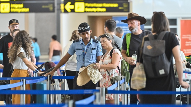 Petugas memberikan informasi kepada penumpang pesawat di Terminal Keberangkatan Internasional Bandara Internasional I Gusti Ngurah Rai, Badung, Bali, Rabu (18/3/2026). [ANTARA FOTO/Fikri Yusuf/agr]