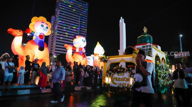 Sejumlah warga menyaksikan pawai obor dan fetival bedug dalam rangka menyambut Hari Raya Idul Fitri 1447 Hijriah di Bundaran HI, Jakarta, Jumat (20/3/2026). [Suara.com/Alfian Winanto]
 