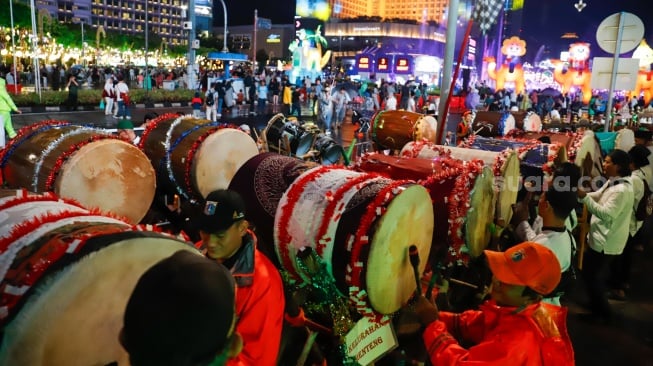 Sejumlah warga menyaksikan pawai obor dan fetival bedug dalam rangka menyambut Hari Raya Idul Fitri 1447 Hijriah di Bundaran HI, Jakarta, Jumat (20/3/2026). [Suara.com/Alfian Winanto]
 