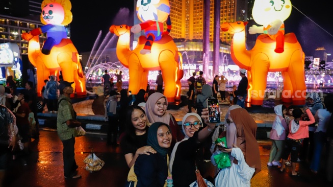 Sejumlah warga menyaksikan pawai obor dan fetival bedug dalam rangka menyambut Hari Raya Idul Fitri 1447 Hijriah di Bundaran HI, Jakarta, Jumat (20/3/2026). [Suara.com/Alfian Winanto]
 