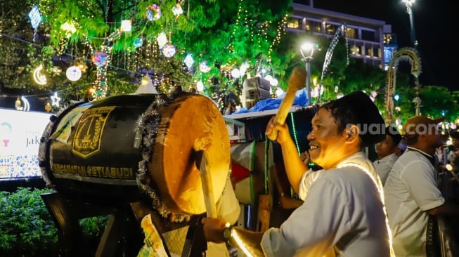 Sejumlah warga menyaksikan pawai obor dan fetival bedug dalam rangka menyambut Hari Raya Idul Fitri 1447 Hijriah di Bundaran HI, Jakarta, Jumat (20/3/2026). [Suara.com/Alfian Winanto]
 
