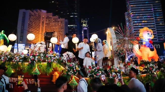 Sejumlah warga menyaksikan pawai obor dan fetival bedug dalam rangka menyambut Hari Raya Idul Fitri 1447 Hijriah di Bundaran HI, Jakarta, Jumat (20/3/2026). [Suara.com/Alfian Winanto]
 