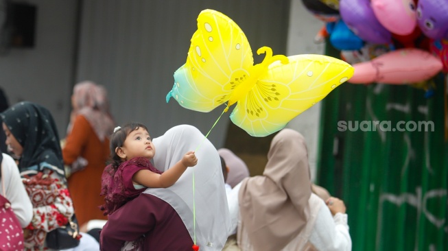 Seorang anak memegang balon saat akan melaksanakan Salat Idul Fitri 1447 Hijriah di Jatinegara, Jakarta, Jumat (21/3/2026). [Suara.com/Alfian Winanto]