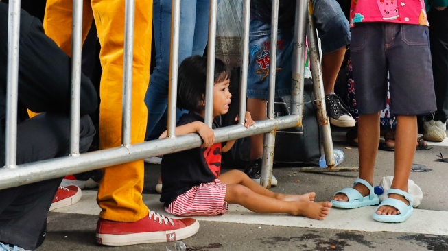 Seorang anak menangis saat mengantre dan menunggu masuk untuk Halal bihalal bersama Presiden di Istana Negara, Jakarta, Sabtu (21/3/2026). [Suara.com/Alfian Winanto]