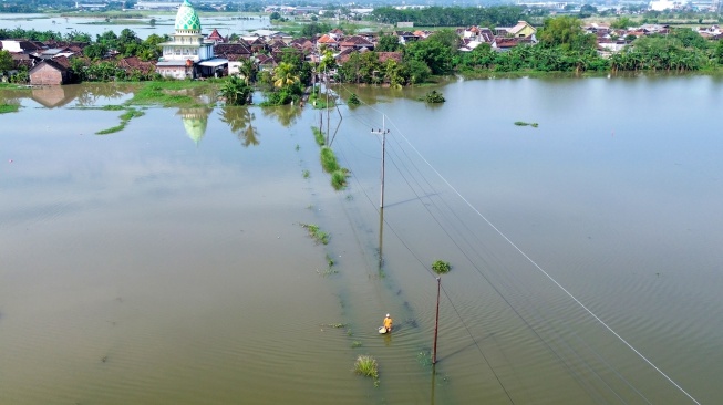 Foto udara seorang warga melintasi jalan yang terendam banjir di Beji, Pasuruan, Jawa Timur, Rabu (25/3/2026). [ANTARA FOTO/Umarul Faruq/tom]