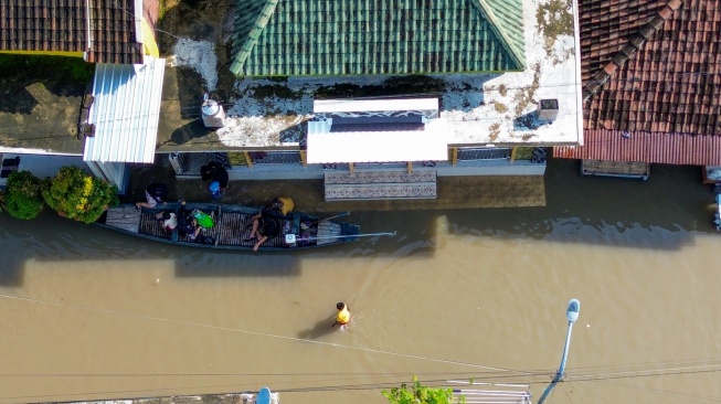 Foto udara warga berjalan dan menggunakan perahu saat banjir di Desa Kedungringin, Beji, Pasuruan, Jawa Timur, Rabu (25/3/2026). [ANTARA FOTO/Umarul Faruq/tom]
