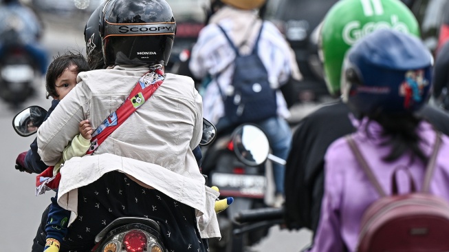 Seorang anak duduk di pangkuan ibunuya saat arus balik sepeda motor di Ciberes, Patokbeusi, Kabupaten Subang, Jawa Barat, Rabu (25/3/2026). [ANTARA FOTO/Fauzan/nz]
