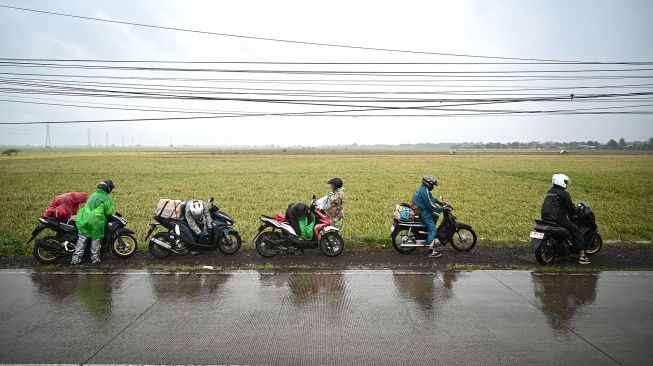 Sejumlah pemudik arus balik sepeda motor berhenti untuk mengenakan jas hujan Jalan Pantura, Kabupaten Subang, Jawa Barat, Rabu (25/3/2026). [ANTARA FOTO/Fauzan/nz]