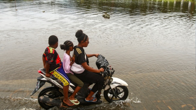 Pengendara motor melintas di jalanan yang tergenang air luapan Danau Sentani di Kalkhote, Asei Besar, Sentani Timur, Kabupaten Jayapura, Papua, Jumat (27/3/2026). [ANTARA FOTO/Gusti Tanati/sgd]