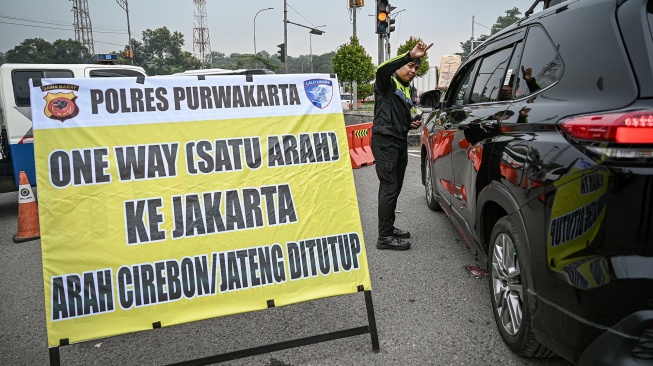 Anggota polisi mengarahkan mobil yang hendak masuk ke tol arah Jawa ke jalur arteri saat sterilisasi jelang penerapan rekayasa lalu lintas satu arah atau one way di ruas Gerbang Tol Cikampek, Karawang, Jawa Barat, Jumat (27/3/2026). [ANTARA FOTO/Fauzan/sgd]