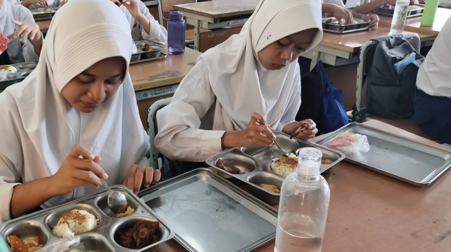 Siswa SMPN 119 Jakarta tengah menikmati jatah Makan Bergizi Gratis (MBG) (Suara.com/Mohammad Rhadzaki Ramadhan)