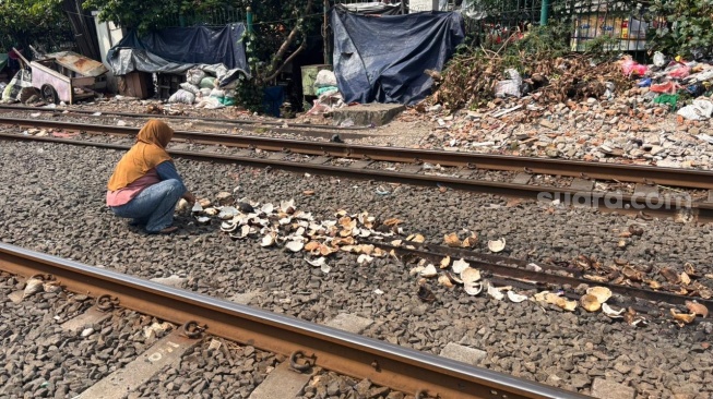 Istri Rosikin (50) saat menjemur batok kelapa untuk dijadikan arang. (Suara.com/Dinda)