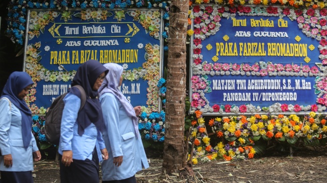Warga melintas di dekat karangan bunga dukacita saat melayat di kediaman almarhum Praka Farizal Rhomadhon, Sidorejo, Lendah, Kulon Progo, D.I Yogyakarta, Selasa (31/2/2026). [ANTARA FOTO/Andreas Fitri Atmoko/tom]
