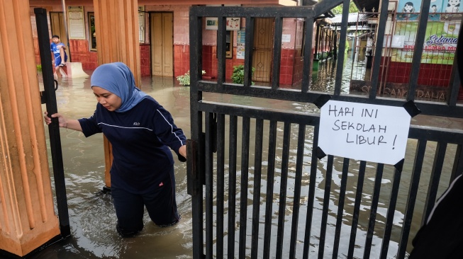 Seorang guru menutup gerbang sekolah yang terdampak banjir di SD Negeri Sanggrahan 01, Kabupaten Sukoharjo, Jawa Tengah, Rabu (15/4/2026). [ANTARAFOTO/Maulana Surya/YU]