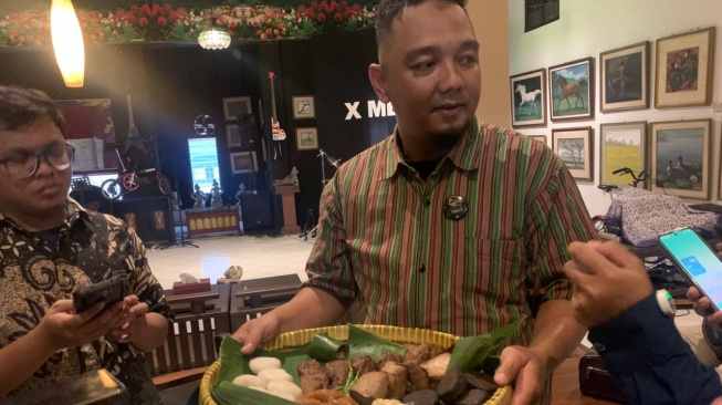 Owner Jadah Tempe Mbah Carik, Angga Kusuma Arybowo, saat menceritakan sejarah perjalanan jadah tempe di outlet Jalan Kalirung, Sleman. (Suara.com/Irwan Febri)