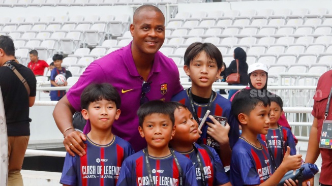 Pemain legenda klub Barcelona, Patrick Kluivert swafoto bersama anak-anak usai berlstih menjelang laga Clash of Legends Jakarta 2026 di Stadion Utama Gelora Bung Karno (SUGBK), Jakarta, Jumat (17/4/2026). [Suara.com/Alfian Winanto]