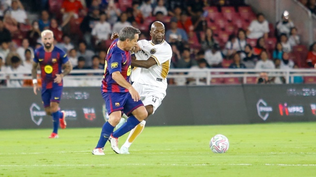 Pemain DRX World Legends, Makelele berebut bola dengan pemain Barca Legends, Sergi Barjuan saat pertandingan sepak bola Clash of Legends antara Barca Legends vs DRX World Legends di Stadion Utama Gelora Bung Karno (SUGBK), Jakarta, Sabtu (18/4/2026). [Suara.com/Alfian Winanto]