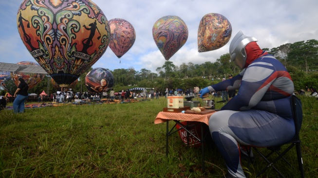 Pengunjung menggunakan kostum Ultraman membuat konten saat penerbangan balon udara pada Festival Balon Udara Boyolali 2026 di lereng Gunung Merapi, Cluntang, Musuk, Boyolali, Jawa Tengah, Sabtu (18/4/2026). [ANTARA FOTO/Aloysius Jarot Nugroho/YU]