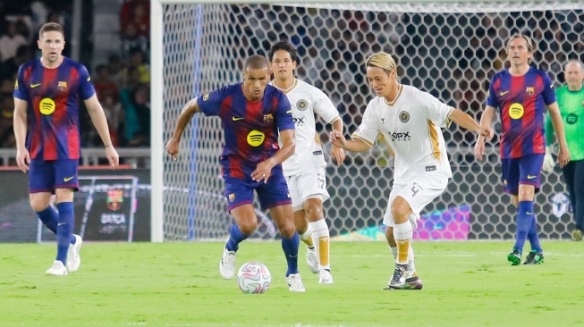 Pemain Barca Legends, Rivaldo membawa bola melewati pemain DRX World Legends saat pertandingan sepak bola Clash of Legends di Stadion Utama Gelora Bung Karno (SUGBK), Jakarta, Sabtu (18/4/2026). [Suara.com/Alfian Winanto]