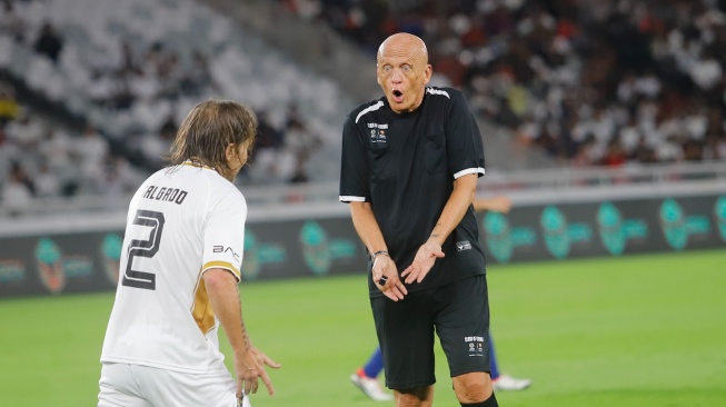 Pelatih DRX World Legends, Michel Salgado protes kepada wasit Pierluigi Collina saat pertandingan sepak bola Clash of Legends antara Barca Legends vs DRX World Legends di Stadion Utama Gelora Bung Karno (SUGBK), Jakarta, Sabtu (18/4/2026). [Suara.com/Alfian Winanto]