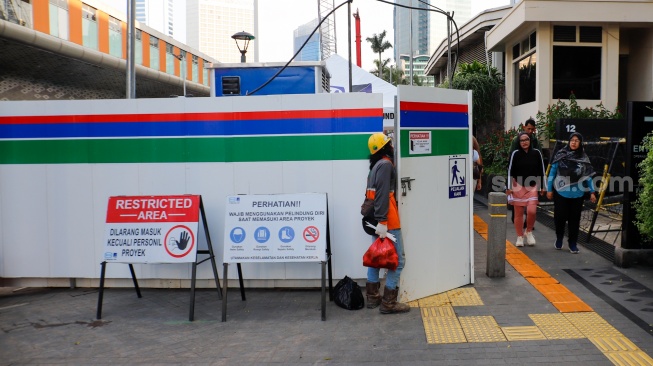 Warga berjalan di pedestrian yang menyempit dampak adanya pengerjaan revitalisasi Stasiun MRT Bundaran HI, Jakarta, Senin (20/4/2026). [Suara.com/Alfian Winanto]