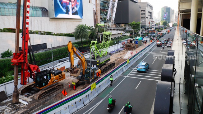 Kendaraan melintas di jalan yang menyempit dampak adanya pengerjaan proyek revitalisasi di Jalan M.H. Thamrin, Jakarta, Senin (20/4/2026). [Suara.com/Alfian Winanto]