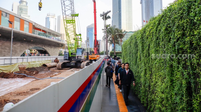 Warga berjalan di pedestrian yang menyempit dampak adanya pengerjaan revitalisasi Stasiun MRT Bundaran HI, Jakarta, Senin (20/4/2026). [Suara.com/Alfian Winanto]