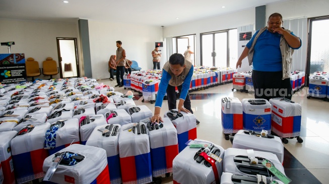 Petugas menyusun koper calon jamaah haji yang memasuki Asrama Haji Pondok Gede, Jakarta, Selasa (21/4/2026). [Suara.com/Alfian Winanto]
