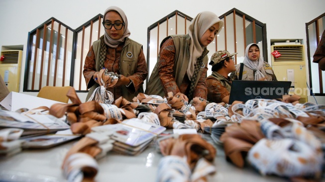 Petugas menyusun tag jemaah calon haji yang mulai memadati Embarkasi Haji Pondok Gede, Jakarta, Selasa (21/4/2026). [Suara.com/Alfian Winanto]
