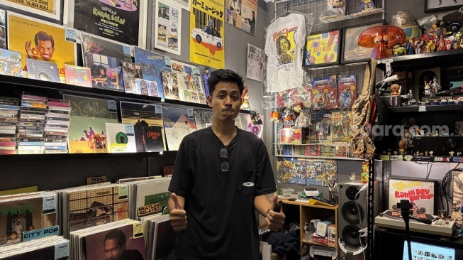 Aduy (24), salah satu penjual vinyl (piringan hitam) memilih tetap bertahan di Pasar Santa, Rabu (22/4/2026). (Suara.com/Dinda Pramesti K)