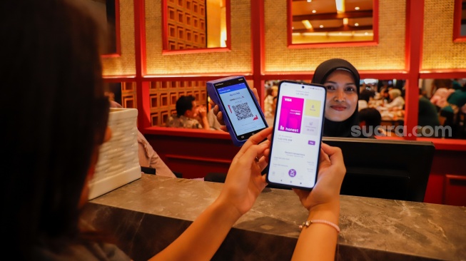 Model melakukan transaksi aplikasi Honest Card saat peluncuran fitur pembayaran QRIS Merchant Presented Mode (MPM) di Jakarta, Selasa (21/4/2026). [Suara.com/Alfian Winanto]

